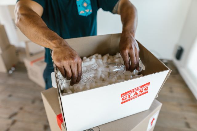 Person properly packs fragile glassware for shipping using packing peanuts