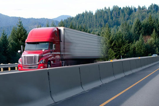 Temperature controlled freight truck on a freeway with trees and mountain landscape