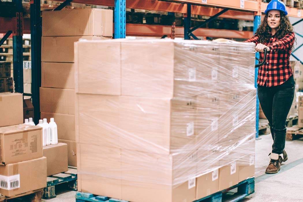 Woman pushes a full pallet in the warehouse